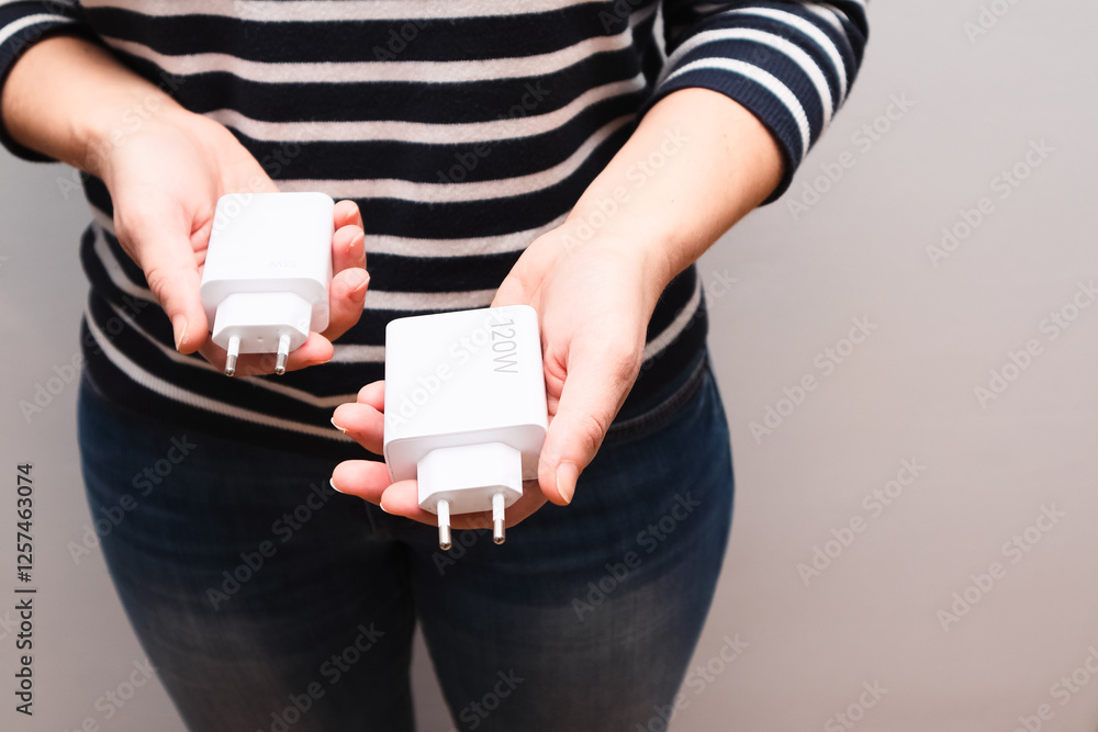Powerful USB chargers for fast charging for a smartphone in the hands of a woman. We compare the sizes of 120 watt and 33 watt chargers Powerful USB chargers for fast charging for a smartphone in the hands of a woman. We compare the sizes of 120 watt and 33 watt chargers