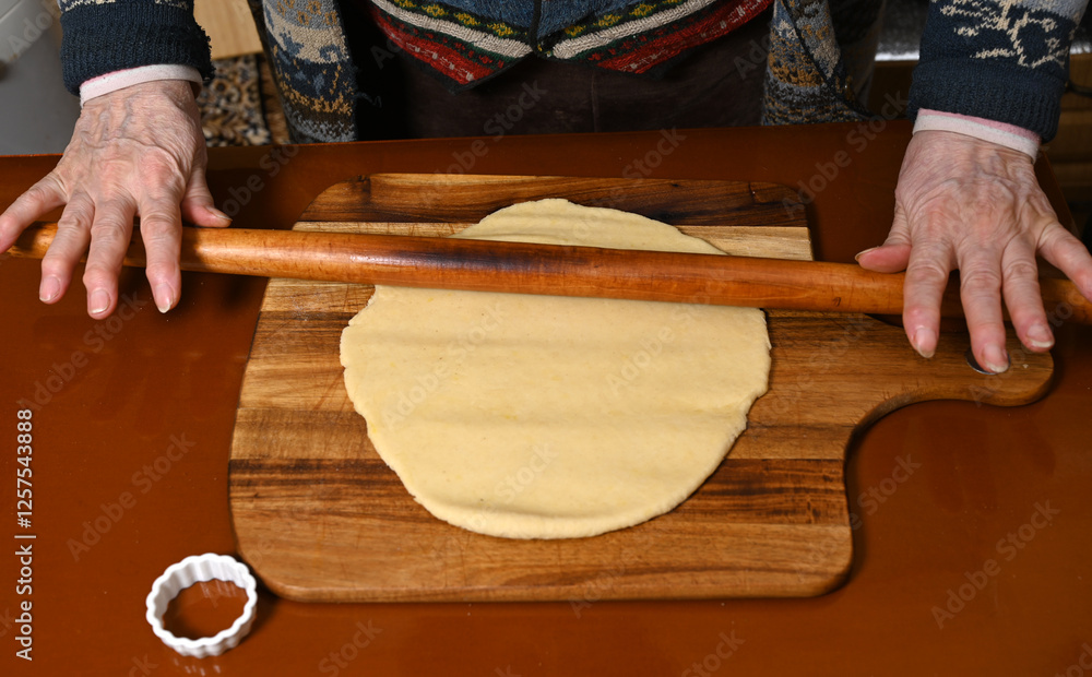 Rolling out dough for traditional pastries at a rustic kitchen table during a winter afternoon