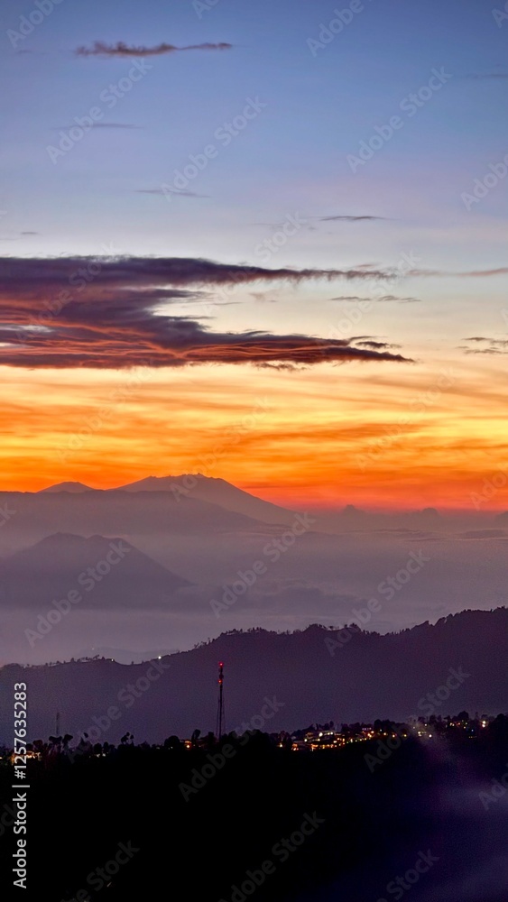 Bromo Pre-Dawn Silhouette with City Lights and Soft Orange Horizon Bromo Pre-Dawn Silhouette with City Lights and Soft Orange Horizon