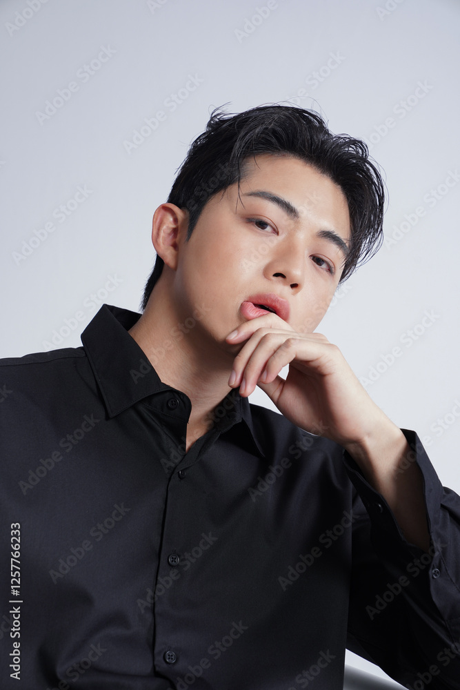 メイクアップをした黒いシャツを着た若い男性のスタイリッシュなポートレート