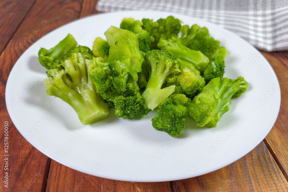 Boiled broccoli pieces on a dish on a rustic table Boiled broccoli pieces on a dish on a rustic table