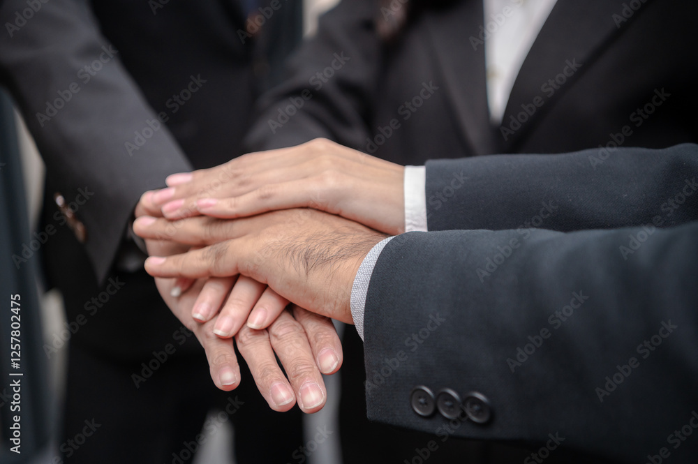 Obraz premium Businessmen and women standing posing together, hands clasped, meeting in office, documents, laptops, sales planning, digital marketing and growth strategies with colorful charts and graphs.