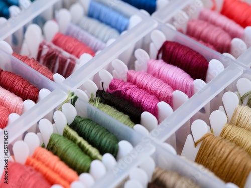 Foto Plastic bobbins with different colour embroidery threads in a plastic sorting box