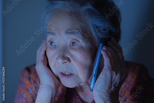 Elderly woman shocked while talking on the phone in blue light.