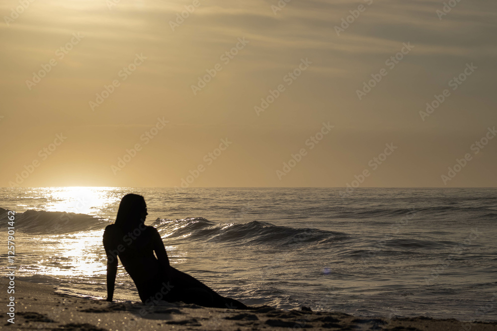 Fototapeta premium Girl silhouette on beach at dawn 1.1