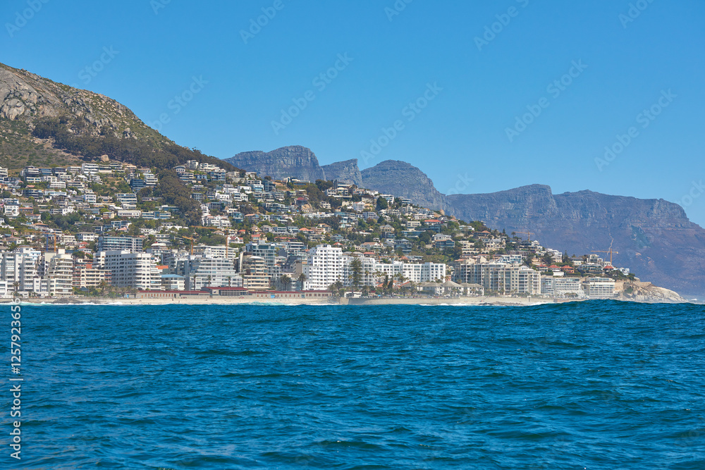 City, ocean and beach with landscape view for sea, coast and urban town or development. Blue sky, background and scenic destination with water, buildings and nature for summer vacation or holiday City, ocean and beach with landscape view for sea, coast and urban town or development. Blue sky, background and scenic destination with water, buildings and nature for summer vacation or holiday