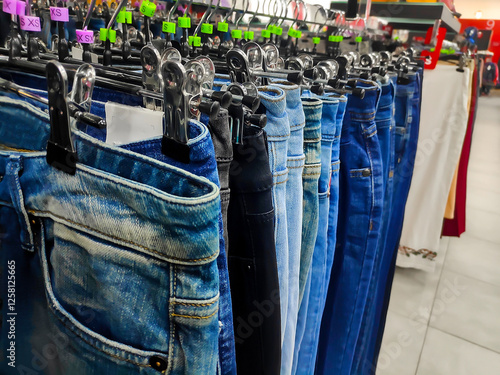 Womens mens jeans pants clothing hanging in racks in store, shop,selecting, checking tops on rails in retail store,shopping mall,choosing new clothes,buying,marketplace center. photo