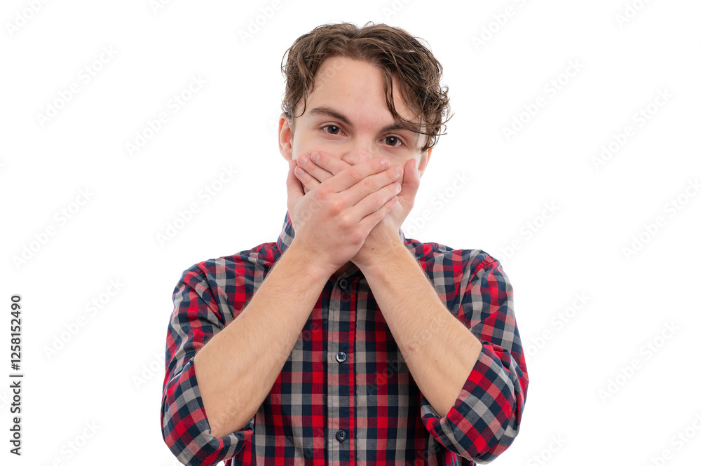 A young man in a plaid shirt covering his mouth with both hands, looking surprised against a white background. A young man in a plaid shirt covering his mouth with both hands, looking surprised against a white background.