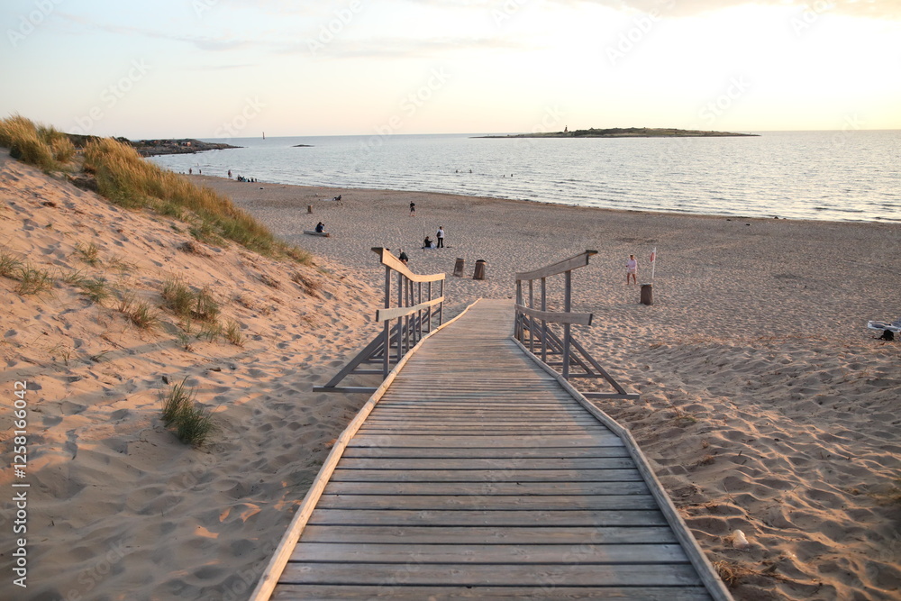Obraz premium A pier heading down to the beach during sunset