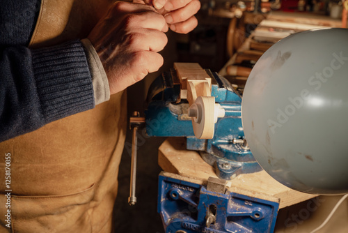 Obraz na plátně Luthier crafting violin scroll using traditional tools and techniques in worksho