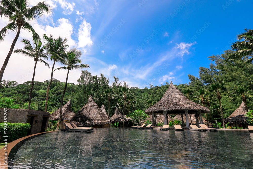 Relaxing oasis with thatched huts by the tranquil pool in Seychelles under a blue sky Relaxing oasis with thatched huts by the tranquil pool in Seychelles under a blue sky