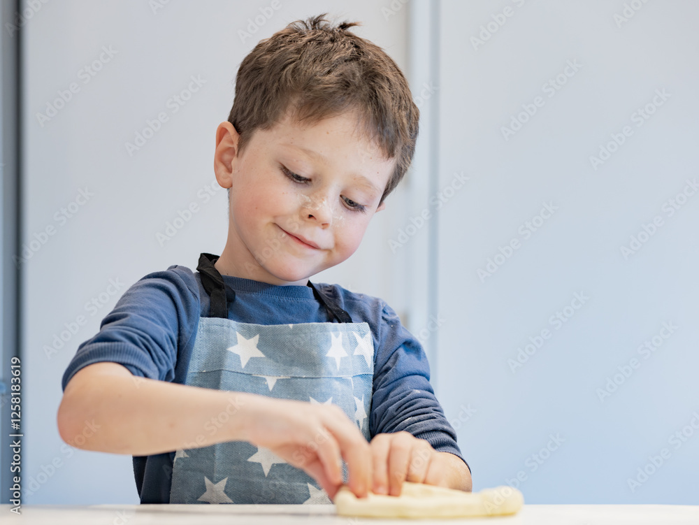 Young child in apron making dough on kitchen counter Young child in apron making dough on kitchen counter