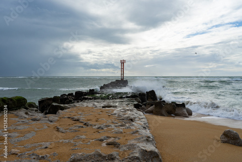 Puissantes, les vagues s’écrasent sur la jetée de la Barre d'Étel, créant un ballet d’écume sous un ciel chargé. La mer en mouvement façonne ce décor brut et indomptable.