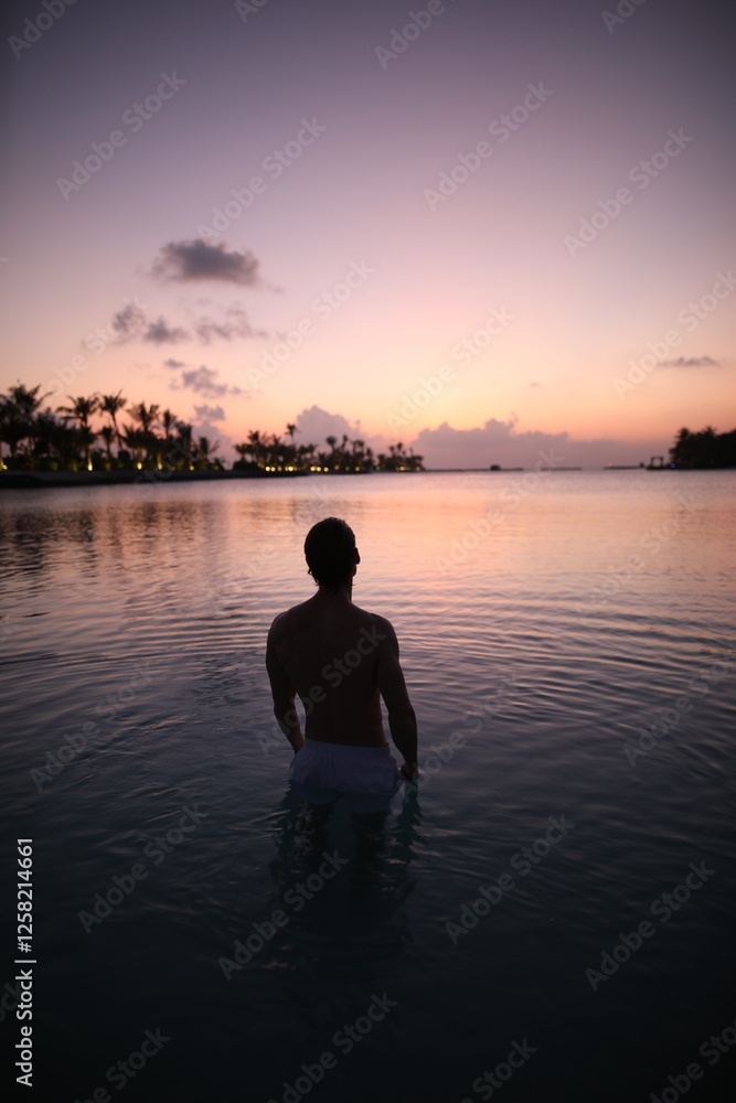 Fototapeta premium Young man in sunset in ocean