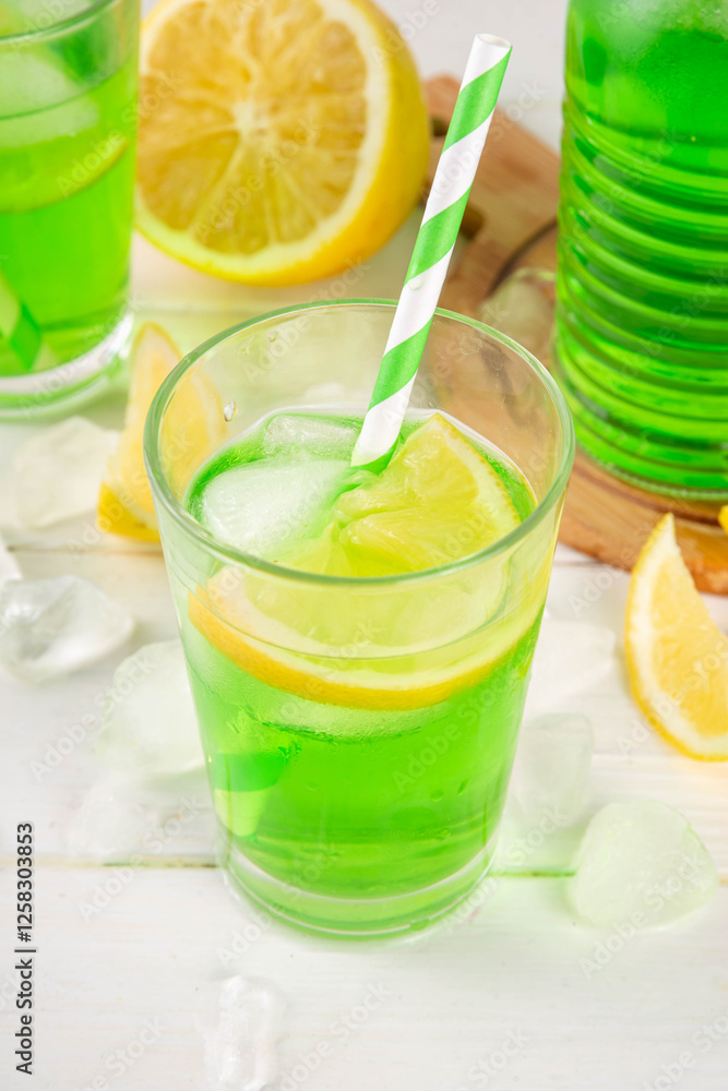 Fototapeta premium Tarragon summer cold lemonade, green aromatic refreshing cocktail with tarragon syrup or liqueur and lemon, on a white wooden kitchen table