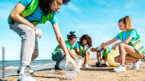 Group of eco volunteers picking up plastic trash on the beach - Activist people collecting garbage protecting the planet - Ocean pollution, environmental conservation and ecology concept.