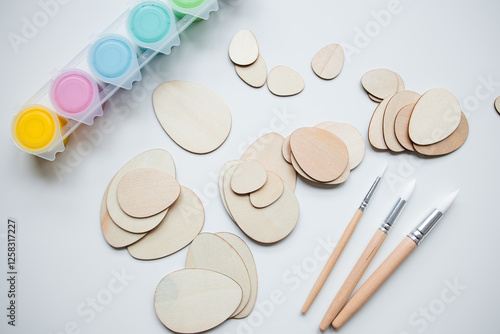 Wooden Easter egg shapes and paints with brushes for DIY crafting projects photo