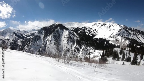 Serene Winter Landscape Featuring A Snowy Mountain, Sparce Trees, And Untouched Snow
