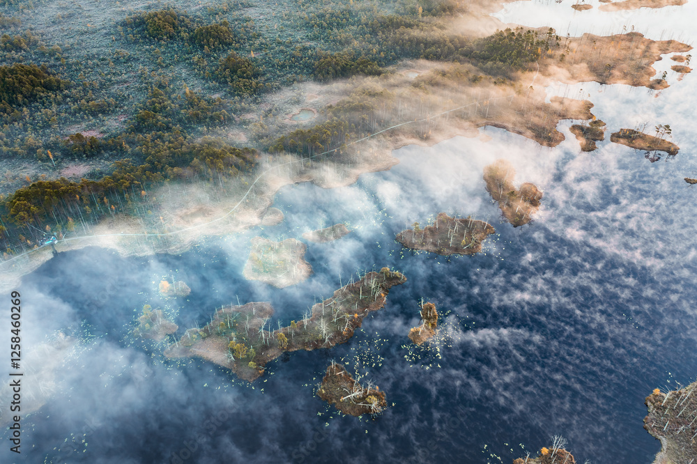 Drone panorama on tiny isles in lake in colorful sunrise colors. Top down view on swamp with isle. Sustainable ecosystem of wetlands.