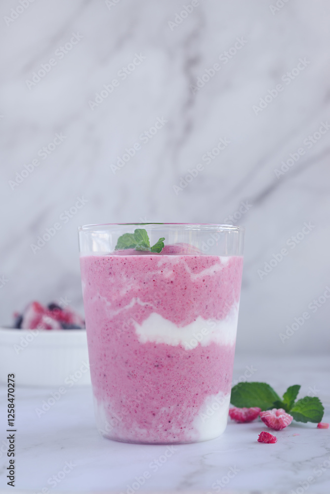 a glass of mixed berry yogurt smoothie on marble table background. a glass of mixed berry yogurt smoothie on marble table background.