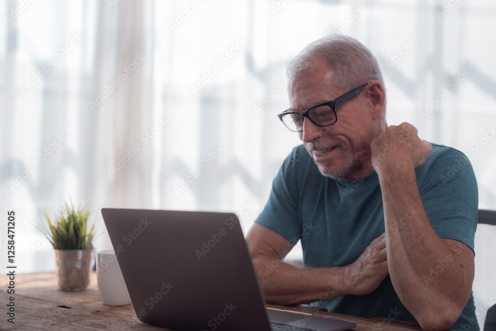 Happy retired man using laptop for working or studying online at home, he is sitting at his wooden desk and smiling while scratching his neck Happy retired man using laptop for working or studying online at home, he is sitting at his wooden desk and smiling while scratching his neck