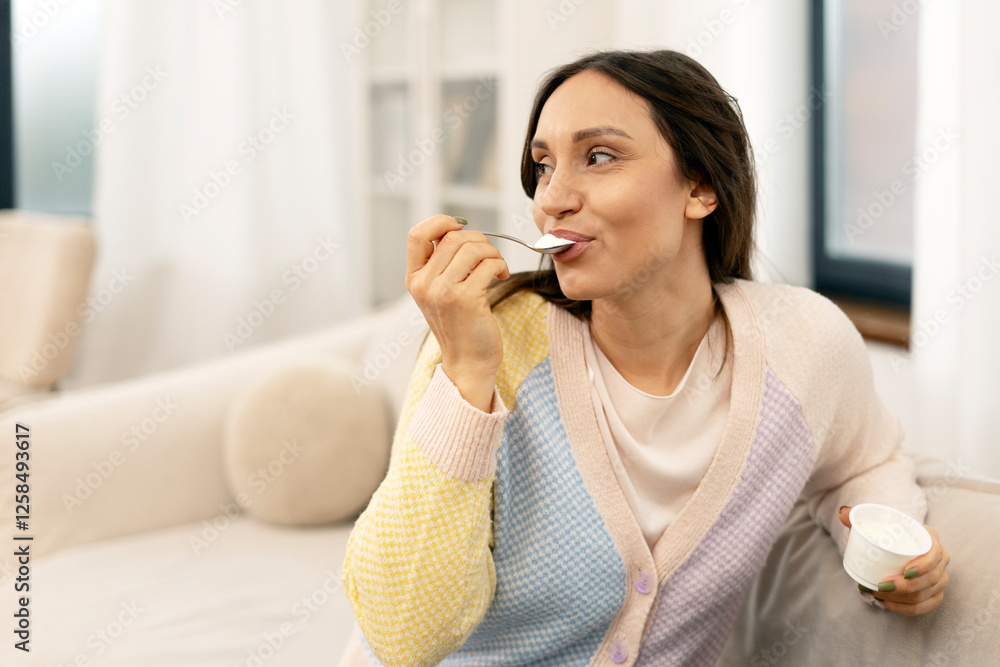 Woman enjoying yogurt on sofa at home: healthy eating habits Woman enjoying yogurt on sofa at home: healthy eating habits