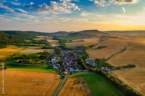 Vibrant German Village Nestled in a Valley Surrounded by Lush Greenery and Picturesque Mountains on a Bright Sunny Day
