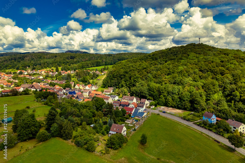 Vibrant German Village Nestled in a Valley Surrounded by Lush Greenery and Picturesque Mountains on a Bright Sunny Day