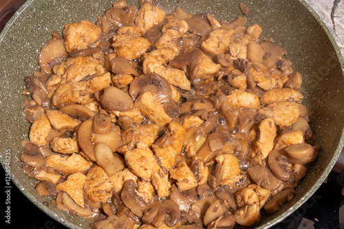 Obraz na płótnie A close-up view of a pan filled with cooked chicken pieces and sliced mushrooms. w salonie