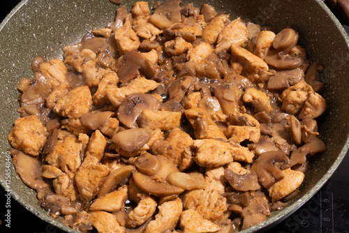 Obraz na płótnie A close-up view of a pan filled with cooked chicken pieces and sliced mushrooms. w salonie