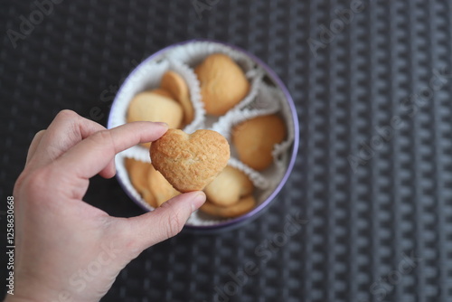 A set of sweet cookies in the shape of hearts as a gift for Valentine's Day. One cookie in hand.