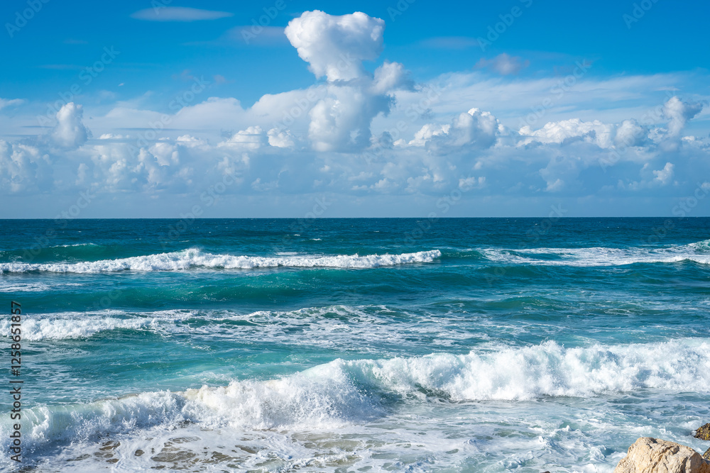 Turquoise sea waves with white foam under blue sky with fluffy clouds. Beautiful seascape, relaxing background for nature and travel projects. Turquoise sea waves with white foam under blue sky with fluffy clouds. Beautiful seascape, relaxing background for nature and travel projects.