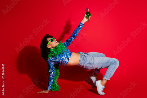 Trendy young woman enjoying leisure against a vibrant red backdrop in stylish attire, capturing dynamic self-expression photo