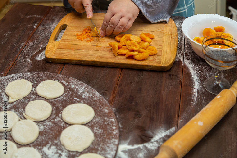 Jewish woman makes a filling of dried fruits for baking on a wooden table Jewish woman makes a filling of dried fruits for baking on a wooden table
