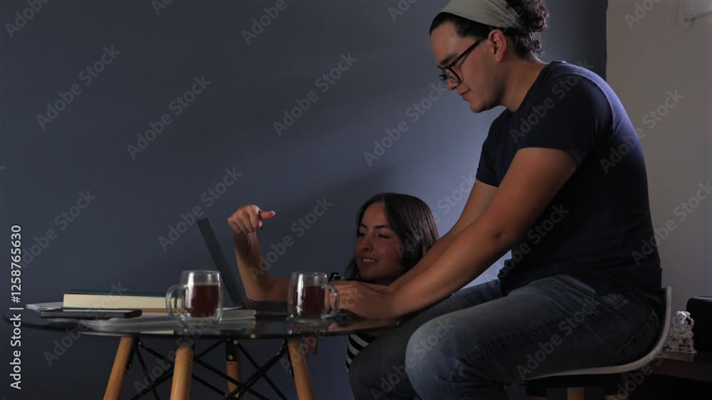 Pareja joven revisando información en el computador con dos tazas de café alegres