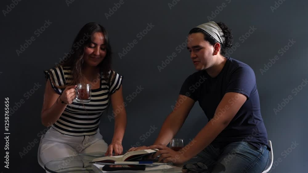 Pareja joven revisando un texto y tomando café alegres y sonrriendo