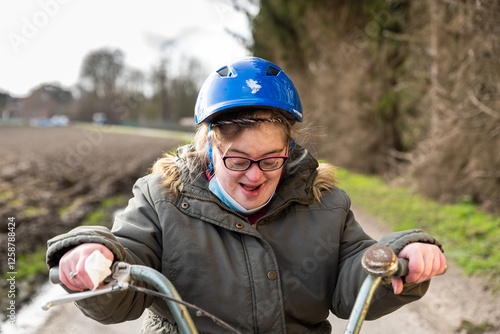 Happy 39 yo woman with the Down Syndrome sitting on her tricycle outdoors, Tienen, Flanders, Belgium photo