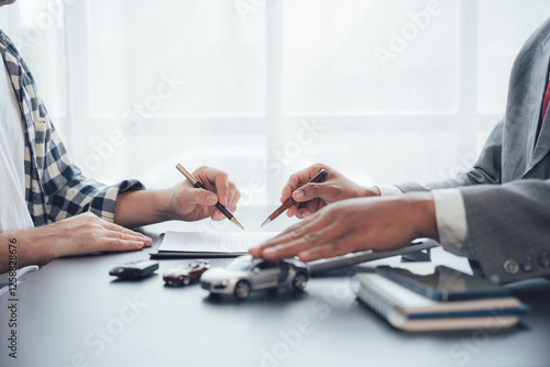 Formalizing the Deal:  A professional business transaction in progress, with two individuals signing a legal document, showcasing commitment, trust, and the finalization of an agreement. photo