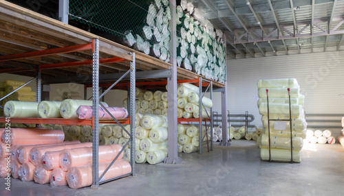 A large selection of fabric rolls on shelves in a furniture factory warehouse, displaying vibrant colors and textures.