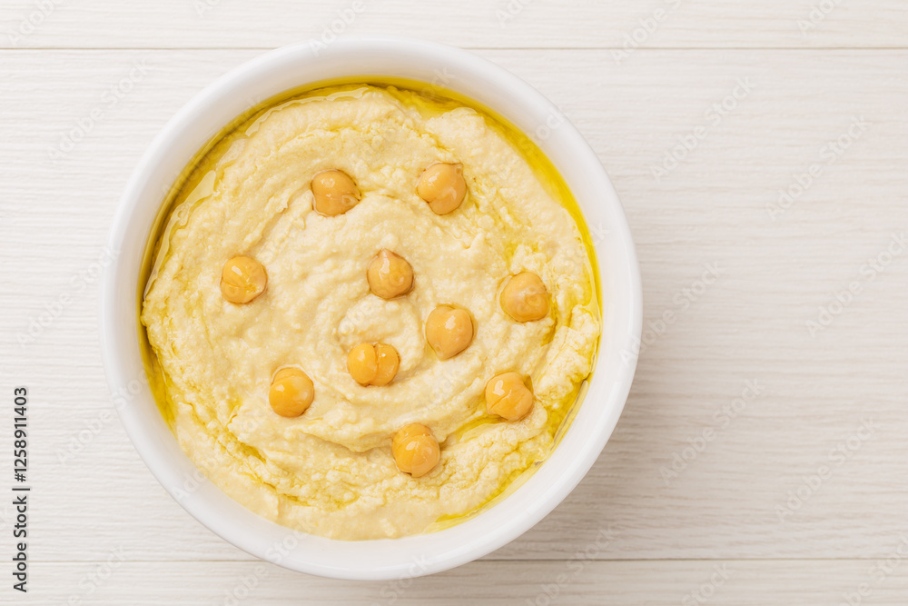 Homemade hummus in a white bowl on a light wooden background. Healthy eating concept. Vegetarian food. Top view. Homemade hummus in a white bowl on a light wooden background. Healthy eating concept. Vegetarian food. Top view.