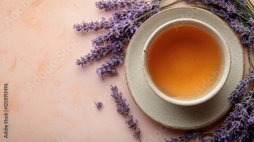 Warm cup of lavender tea surrounded by dried lavender on soft pastel background
