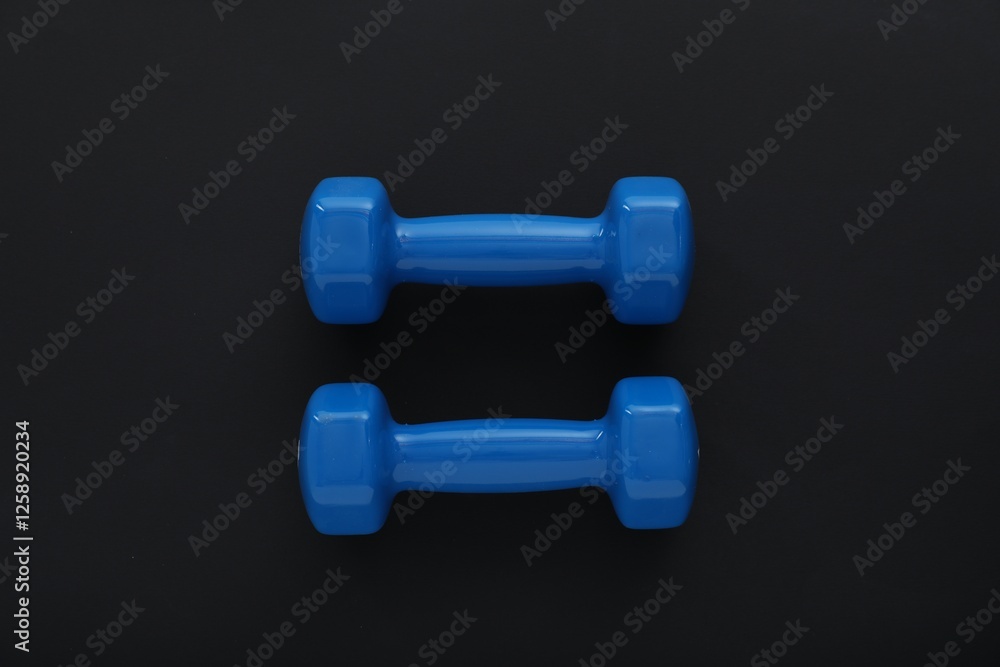 Dumbbells on black background, top view. Sports equipment Dumbbells on black background, top view. Sports equipment
