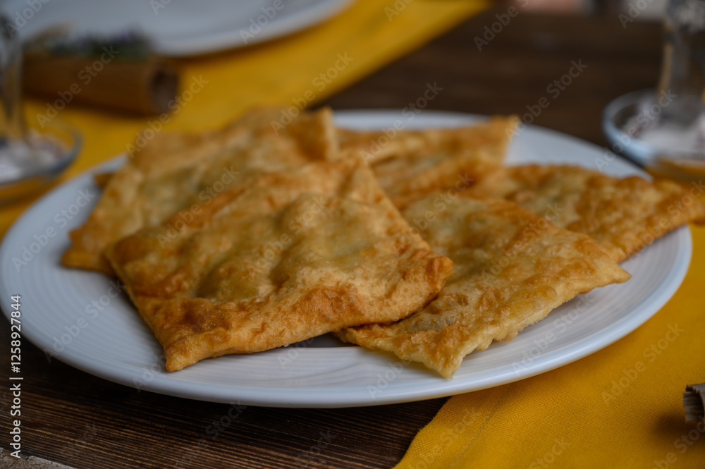 Delicious freshly fried pastries served on a white plate with a vibrant yellow tablecloth Delicious freshly fried pastries served on a white plate with a vibrant yellow tablecloth