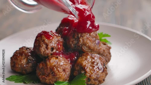 Prepared cranberry sauce is poured over Swedish meatballs. Close-up. High quality 4k footage