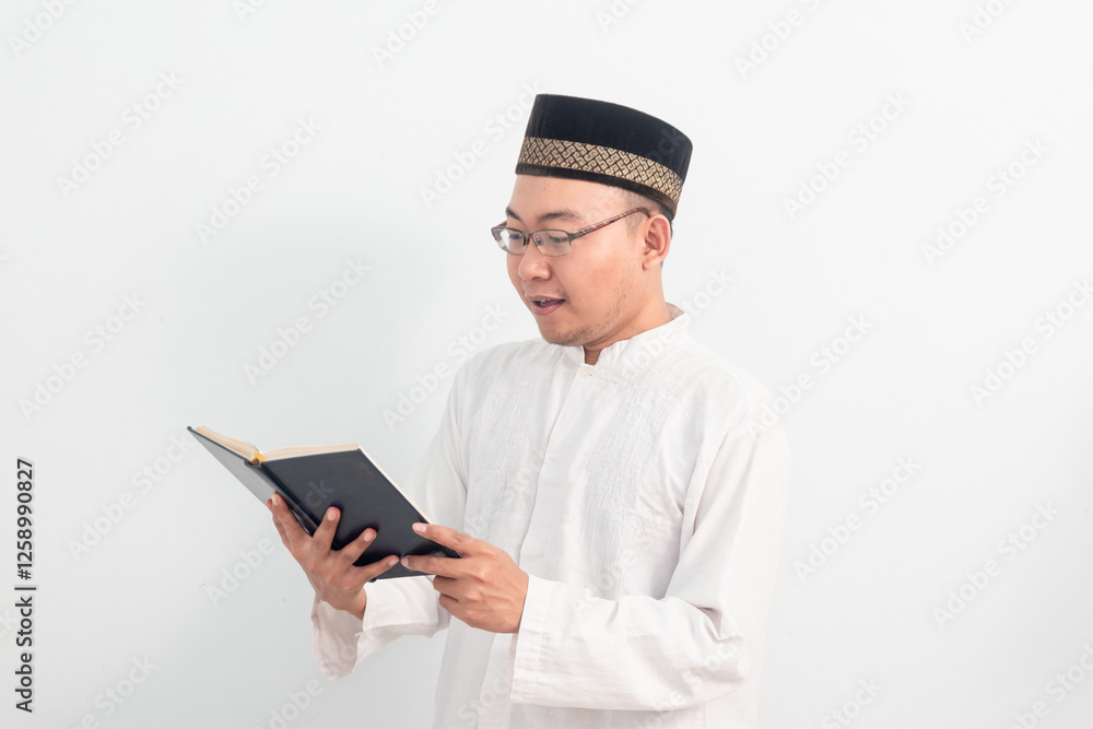 Asian Muslim man wearing white clothes reading quran during Ramadan Eid Al Fitr and eid adha days celebration isolated white background. Islamic celebration concept.. Asian Muslim man wearing white clothes reading quran during Ramadan Eid Al Fitr and eid adha days celebration isolated white background. Islamic celebration concept..