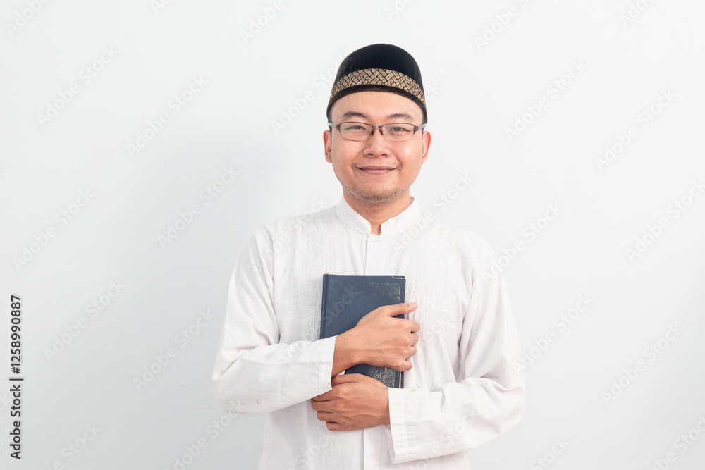 Asian Muslim man wearing white clothes holding quran during Ramadan Eid Al Fitr and eid adha days celebration isolated white background. Islamic celebration concept.. Asian Muslim man wearing white clothes holding quran during Ramadan Eid Al Fitr and eid adha days celebration isolated white background. Islamic celebration concept..