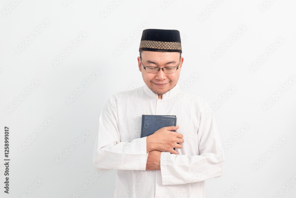 Asian Muslim man wearing white clothes holding quran during Ramadan Eid Al Fitr and eid adha days celebration isolated white background. Islamic celebration concept.. Asian Muslim man wearing white clothes holding quran during Ramadan Eid Al Fitr and eid adha days celebration isolated white background. Islamic celebration concept..