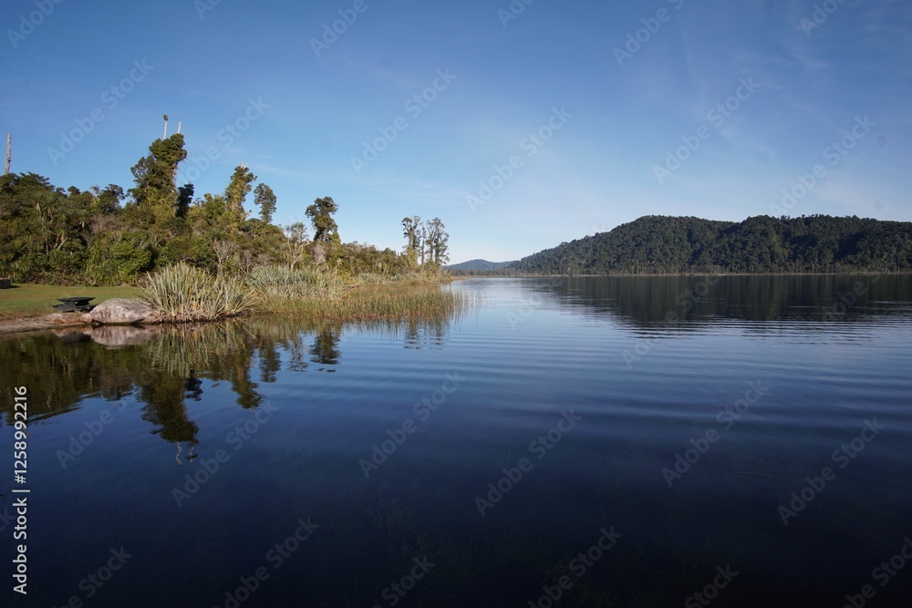 Obraz premium Serene lake with lush greenery in New Zealand