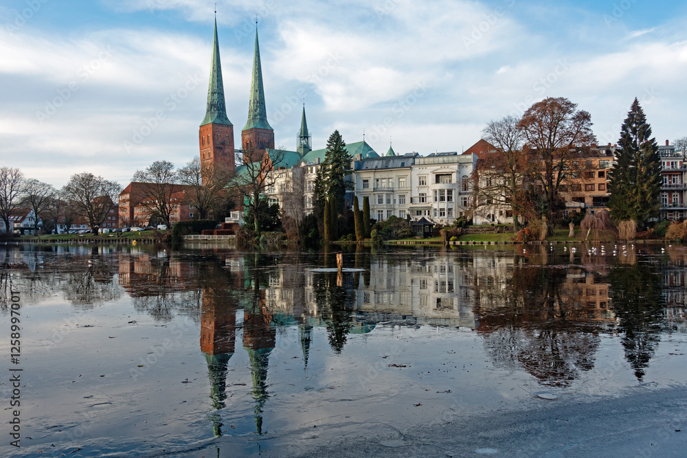 Obraz premium Der Lübecker Dom spiegelt sich im Winter im vereisten Mühlenteich, Deutschland