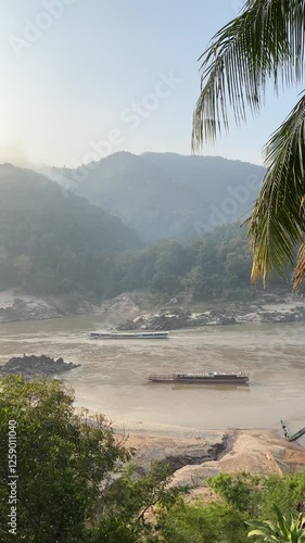 Sunrise view of the Mekong River in mist and slow boats on the road to Luang Prabang, Laos
